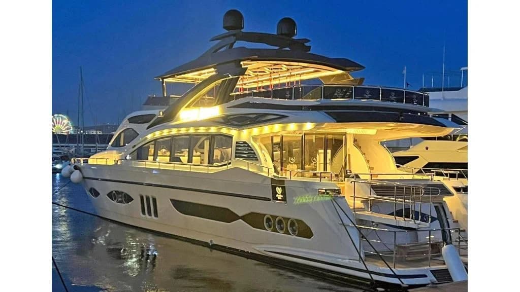 Illuminated motor yacht berthed in a marina at dusk